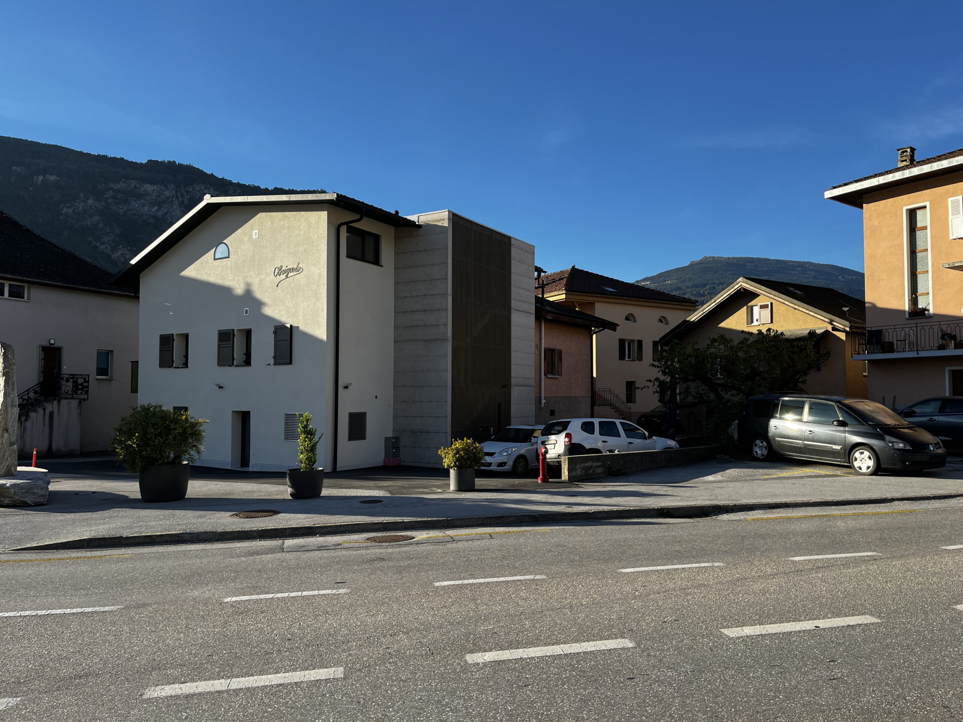 vue extérieure, cage d'escalier béton apparent, façade métallique perforée, couleur dorée, soleil et architecture, architecture moderne, confort d'utilisation, distribution avec ascenseur, matériaux durables, isolation des façades, efficience énergétique, transformation d'appartement, architecte moderne valais, architecte Sion, architecture à Saint-Léonard, transformation en valais