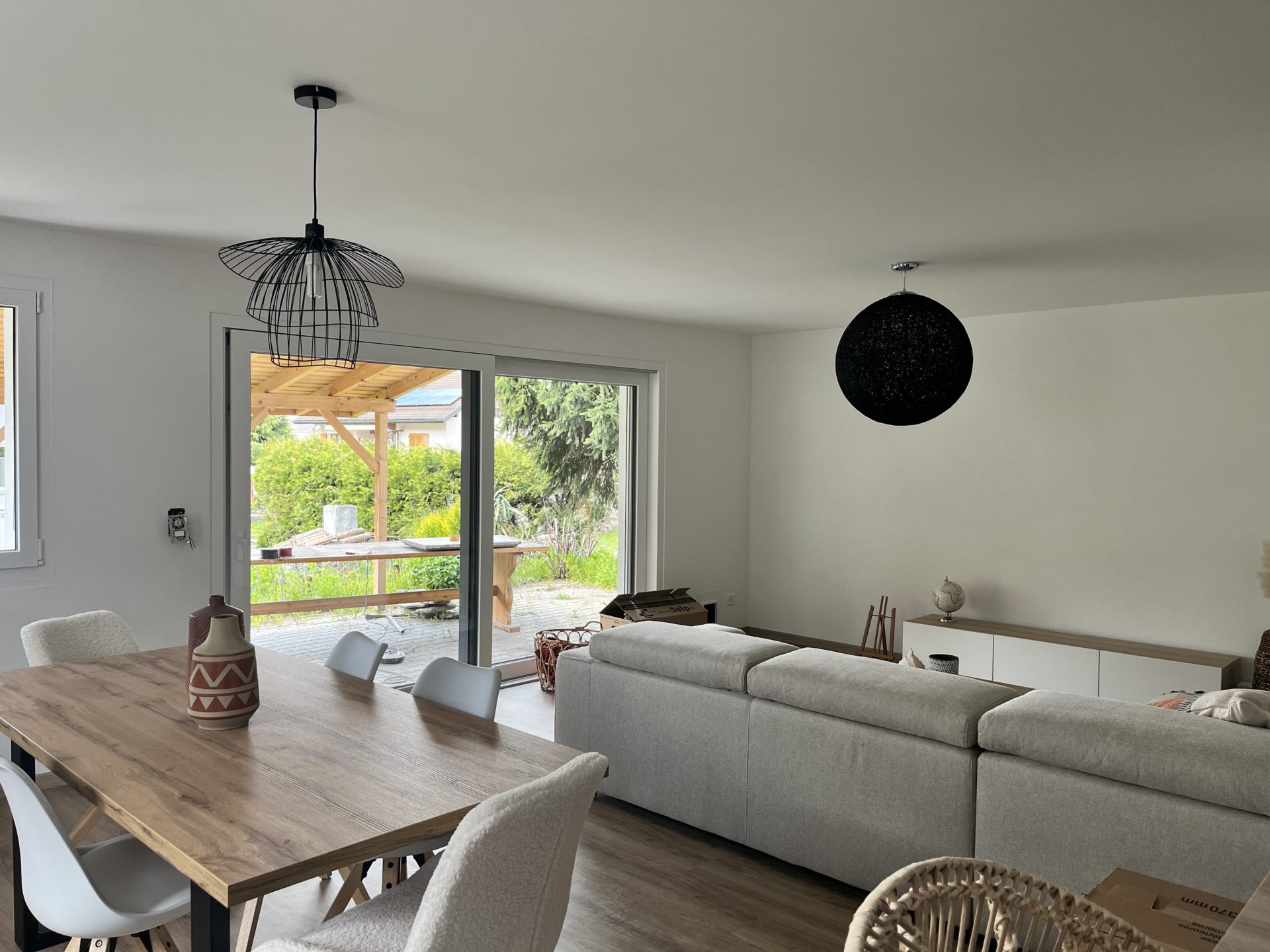 séjour avec espace extérieur, aménagement intérieur contemporain, aménagement chaleureux, architecture, baie vitrée, relation à l'extérieure, verdure et nature, transformation à Saint-Léonard, architecture moderne, ambiance chaleureuse, matériaux modernes, espace lumineux, architecte Sion, architecte valais, transformation valais